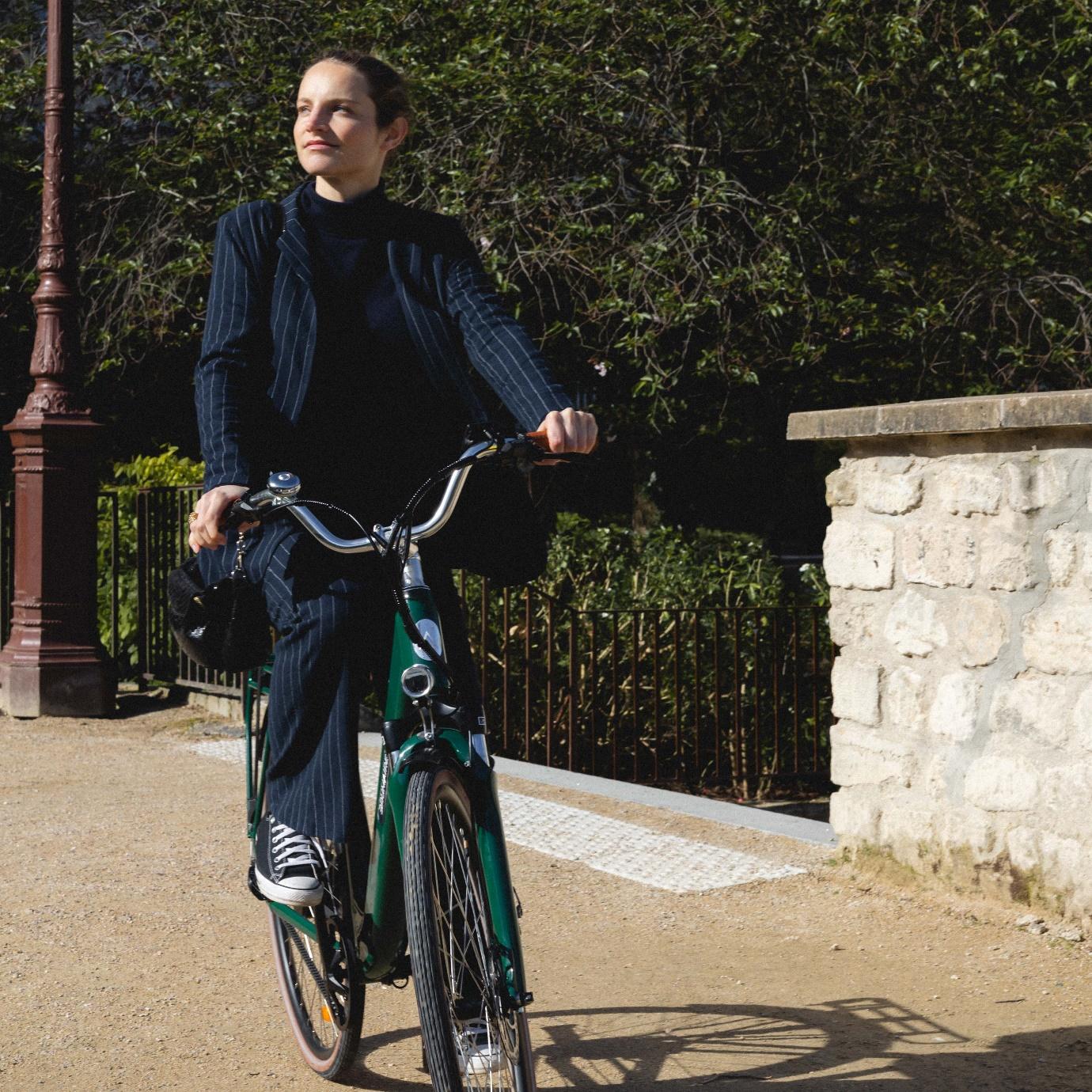Un vélo électrique de ville vert avec une femme dessus
