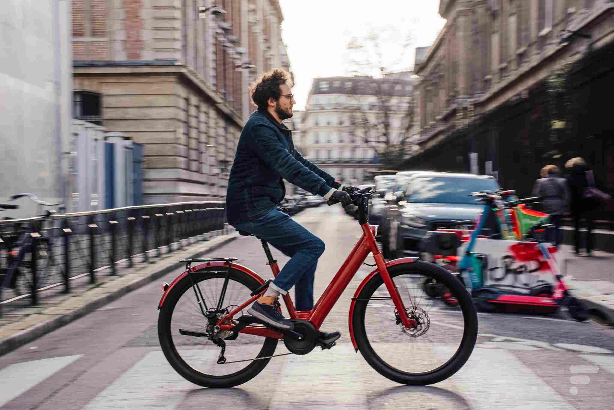 Un homme à vélo électrique rouge avec un panier sur la route