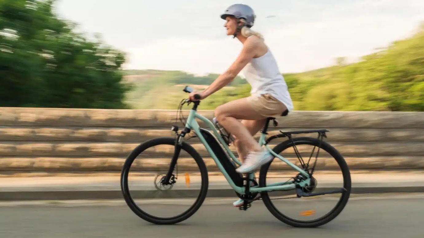 Une femme équipée qui roule sur un vélo bleu
