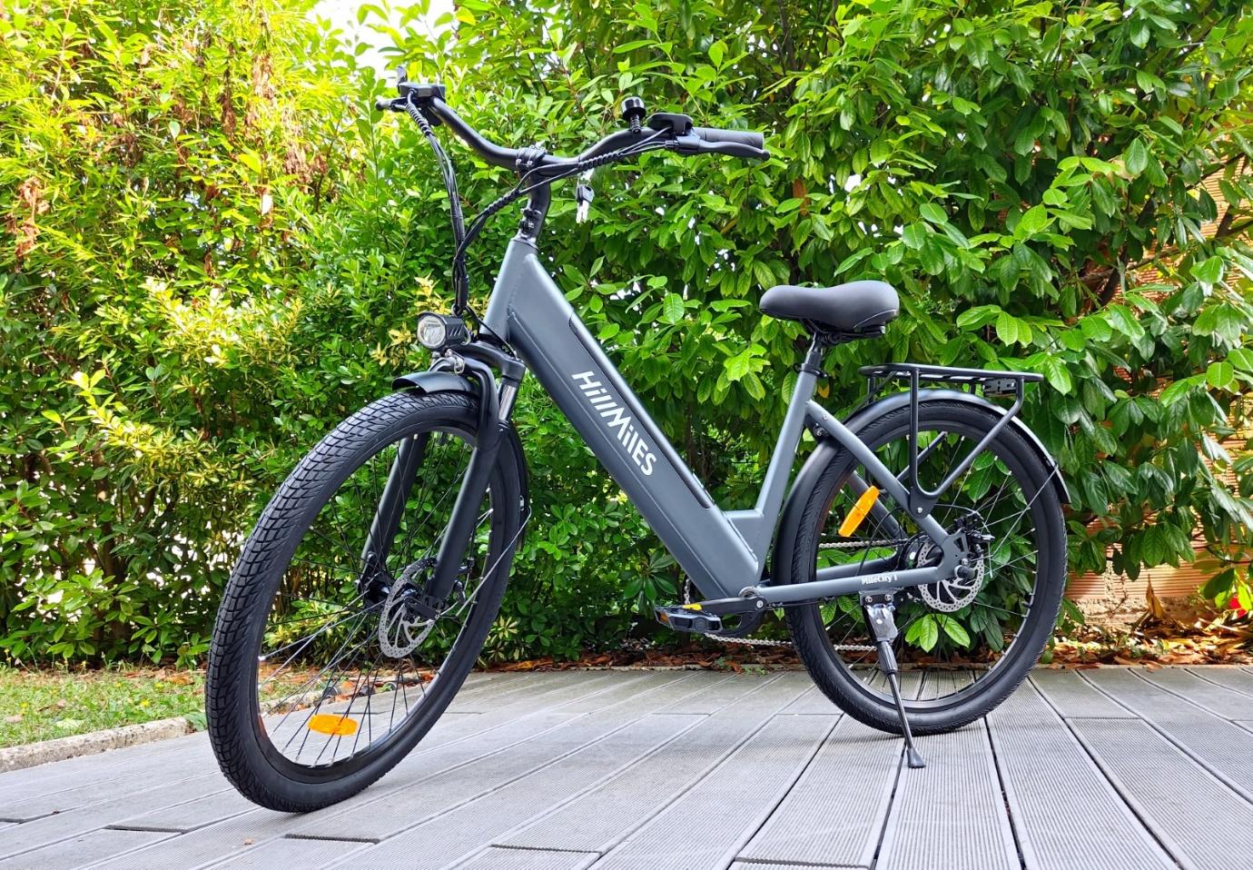Un vélo électrique gris devant des buissons